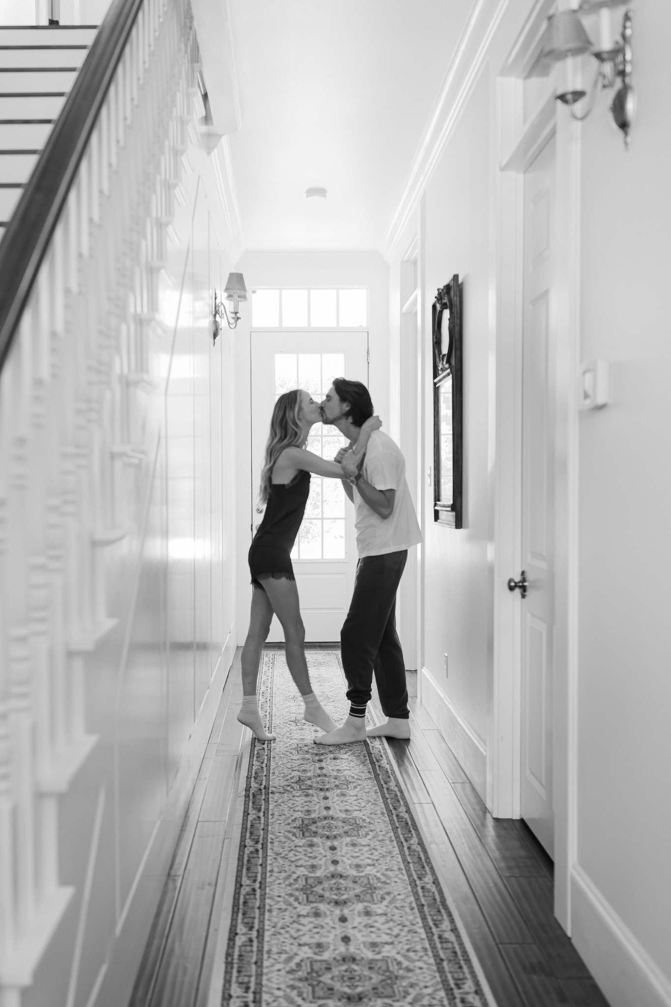 Black and white photo of a couple kissing in a long hallway
