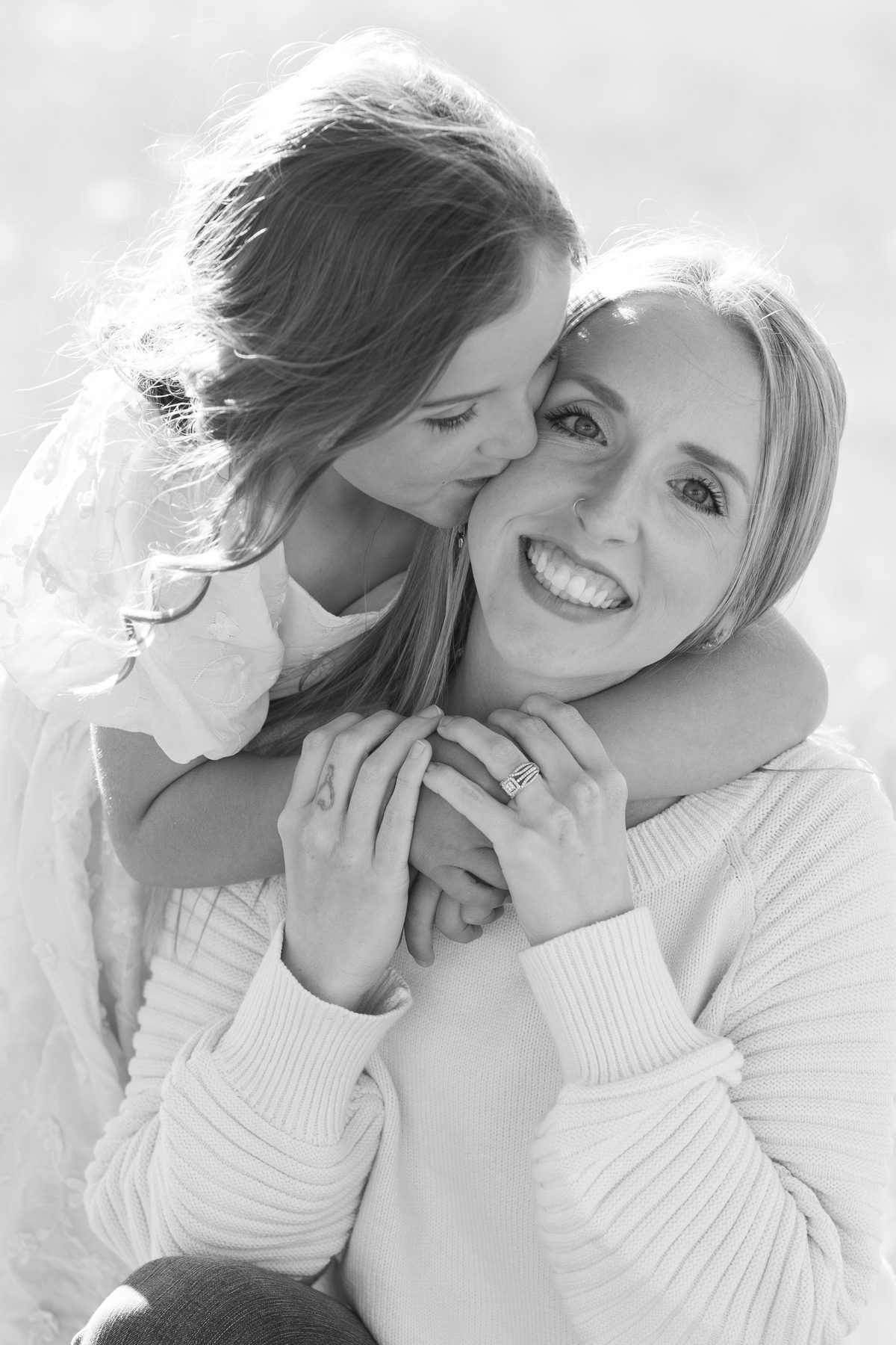 Black and white portrait of a daughter kissing her mom's cheek