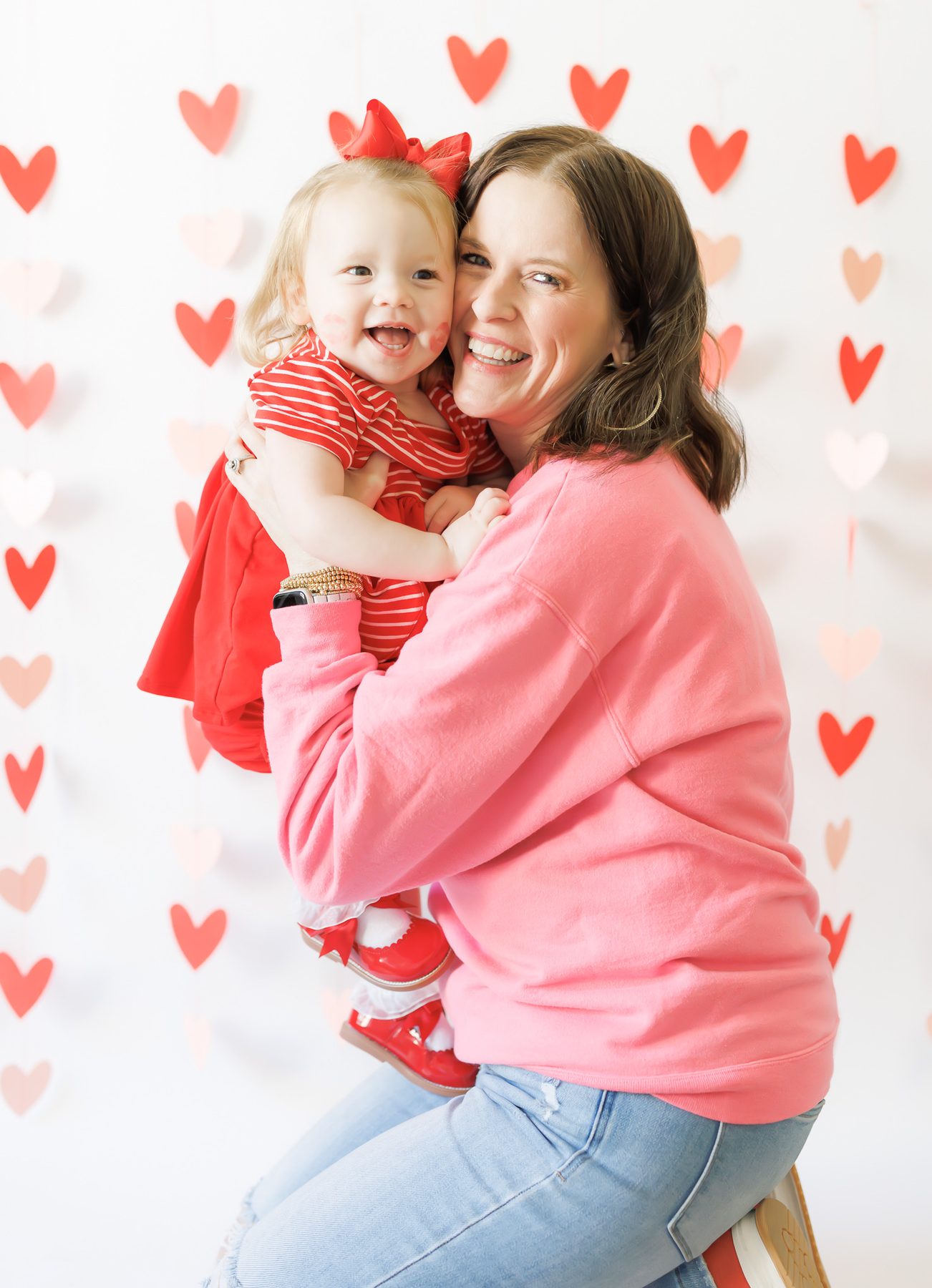 Mom and toddler in front of a Valentine hearts backdrop