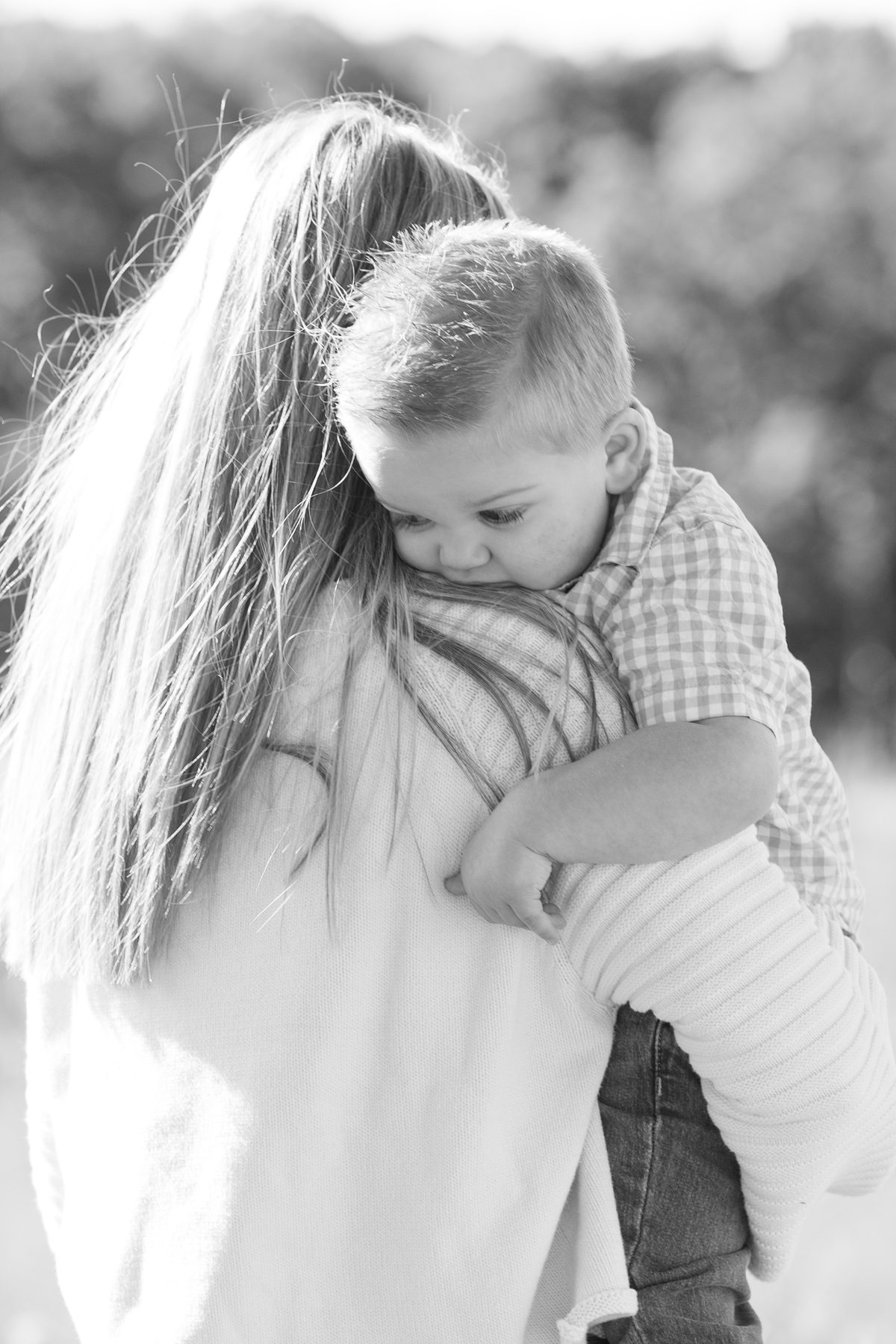 Black and white portrait of a boy resting on his mom's shoulder