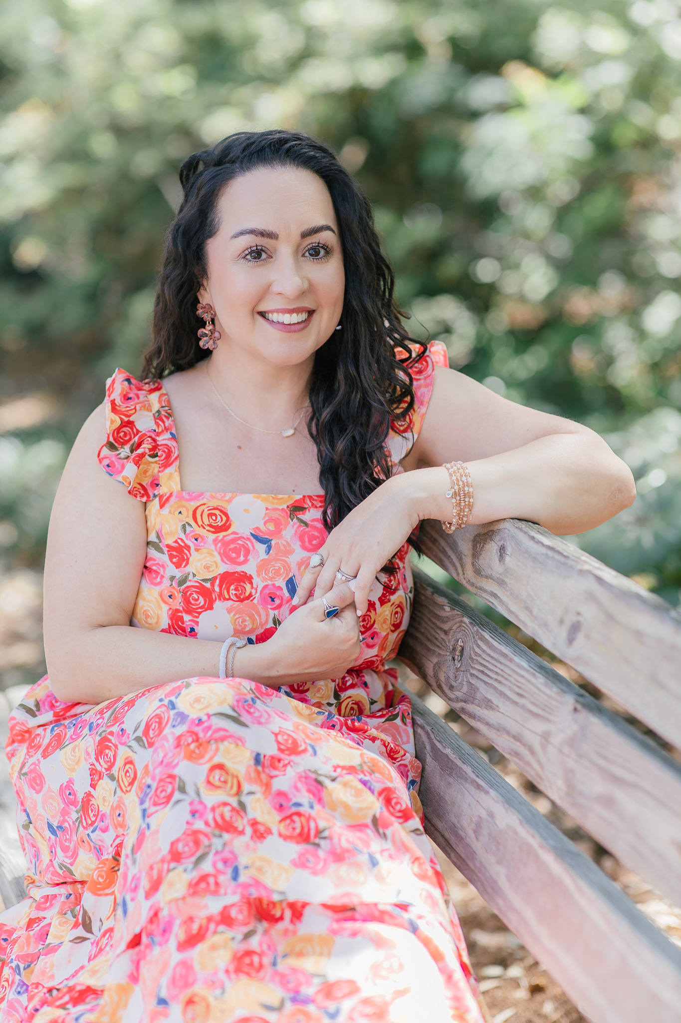 Woman in a floral dress smiling on a wooden bench