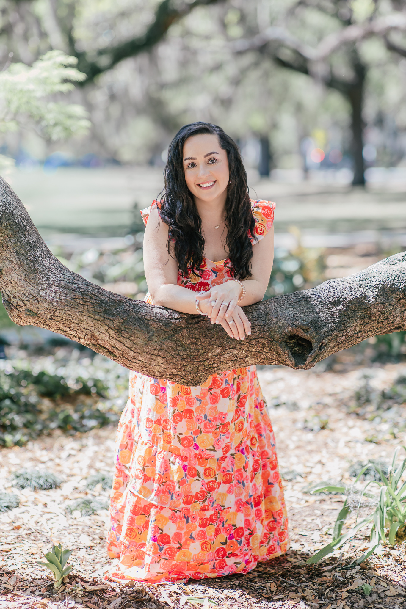 Woman in a floral dress leaning on an oak branch