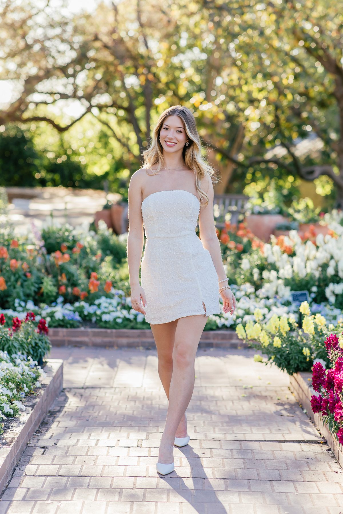 Senior portrait walking through the garden in a white dress