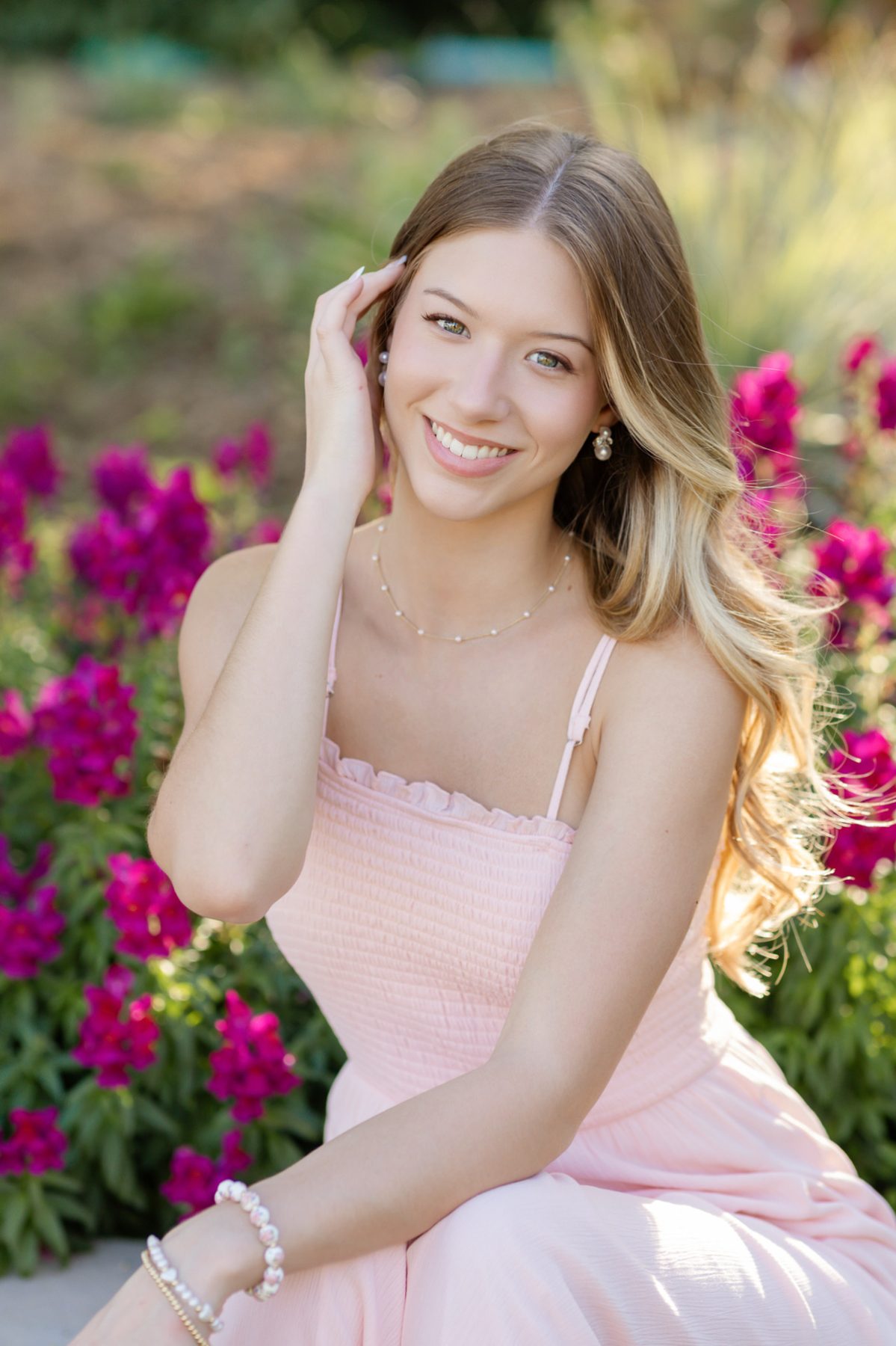 Smiling senior portrait in pink, seated